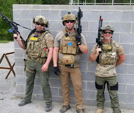 Matt Roberts in Tactical Gear holding a rifle next to two other SWAT operators