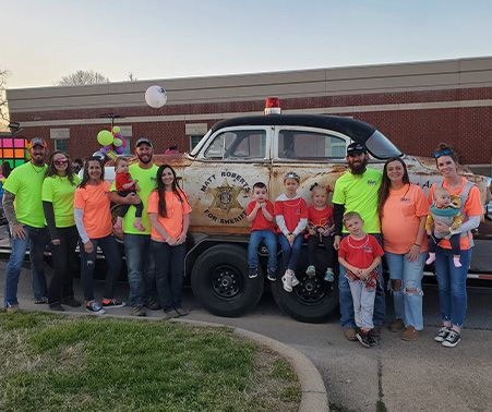 Matt Roberts & Family next to a car at the Neon Parade